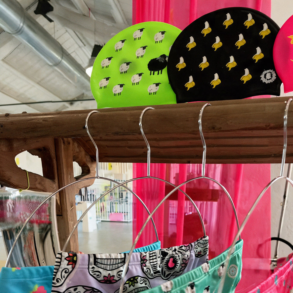 Cuffie da nuoto fluo e costumi stampati sugli scaffali del negozio